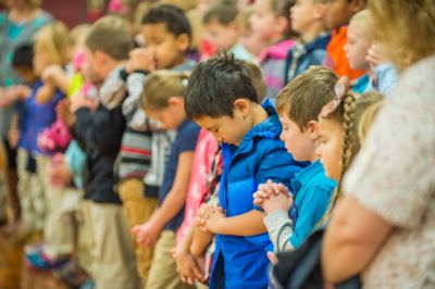 Elementary-age students at Nampa Christian Schools pray together at chapel